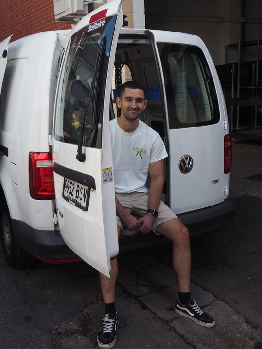 Man sitting inside a white van with open door, visible Volkswagen logo.