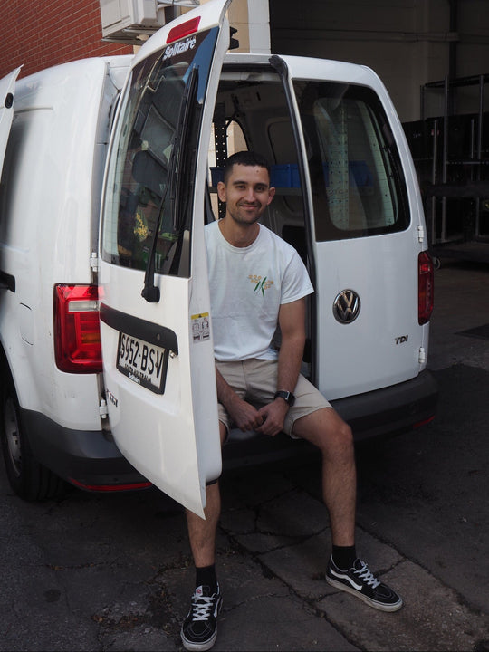 Man sitting inside a white van with open door, visible Volkswagen logo.