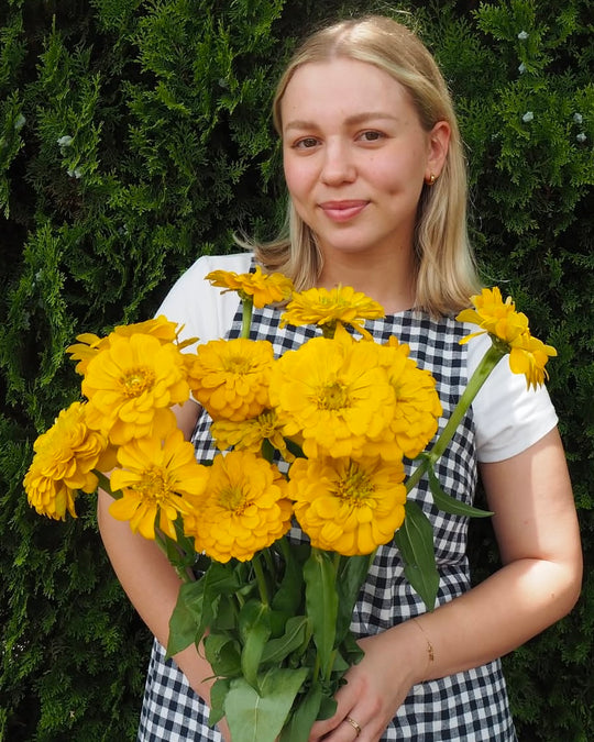 Woman holding a bouquet of yellow flowers against a green background