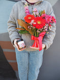 Load image into Gallery viewer, Person holding a bouquet of flowers and a small gift box on a gray background