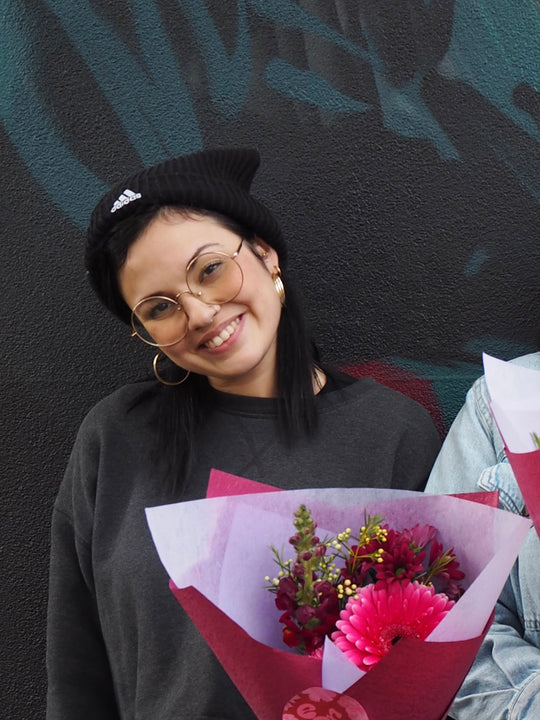 Person holding a bouquet of flowers against a dark textured wall