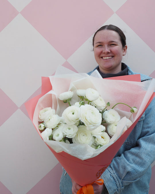 Person holding a bouquet of white flowers against a pink and white checkered background