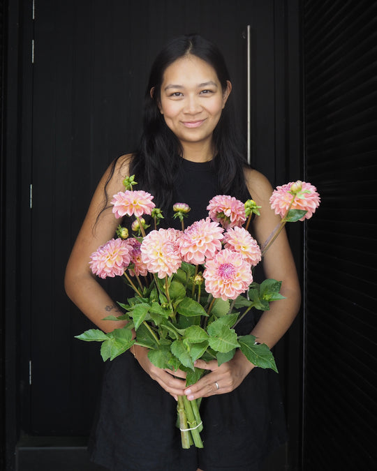 Woman holding a bouquet of pink flowers against a black background