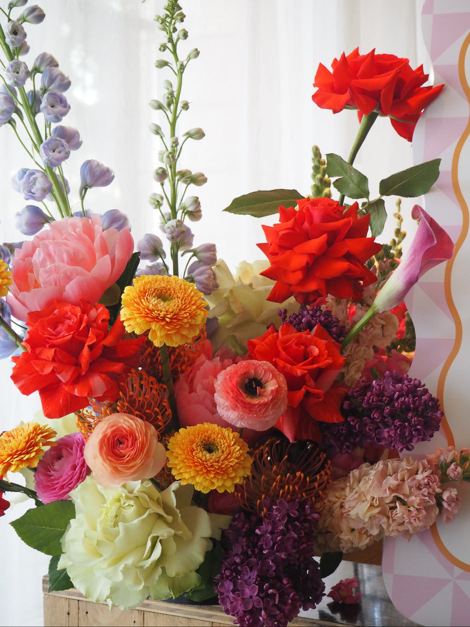 Colorful arangement of flowers with a white curtain background