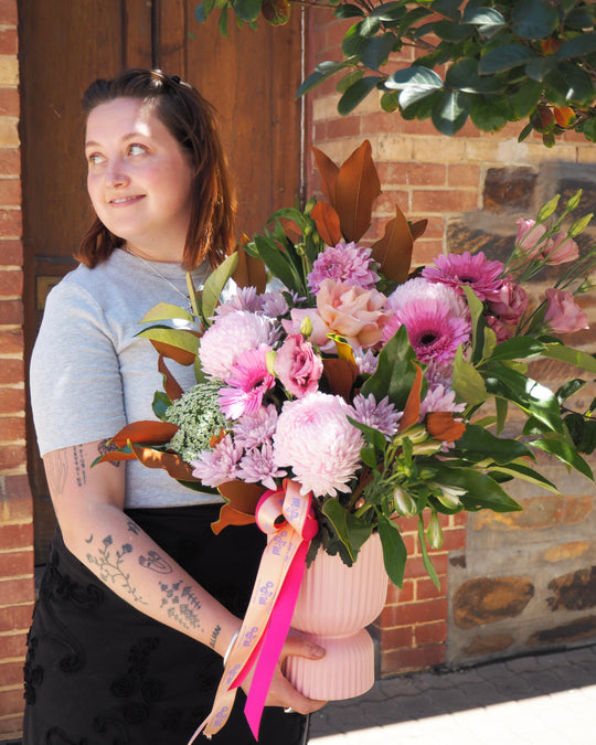 Person holding a large bouquet of flowers in front of a brick wall