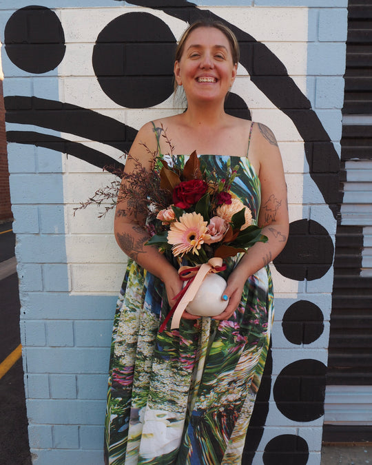 Person holding flowers in front of a polka dot mural