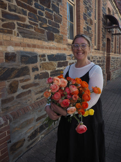 Person holding a bouquet of flowers in front of a brick wall