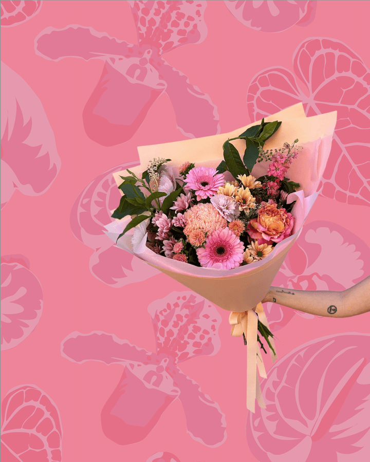Bouquet of flowers held against a pink background with flower patterns