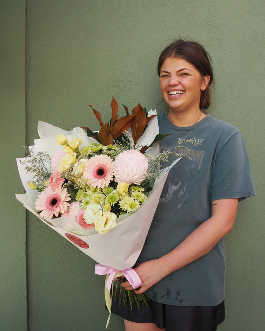 Person holding a bouquet of flowers against a green wall