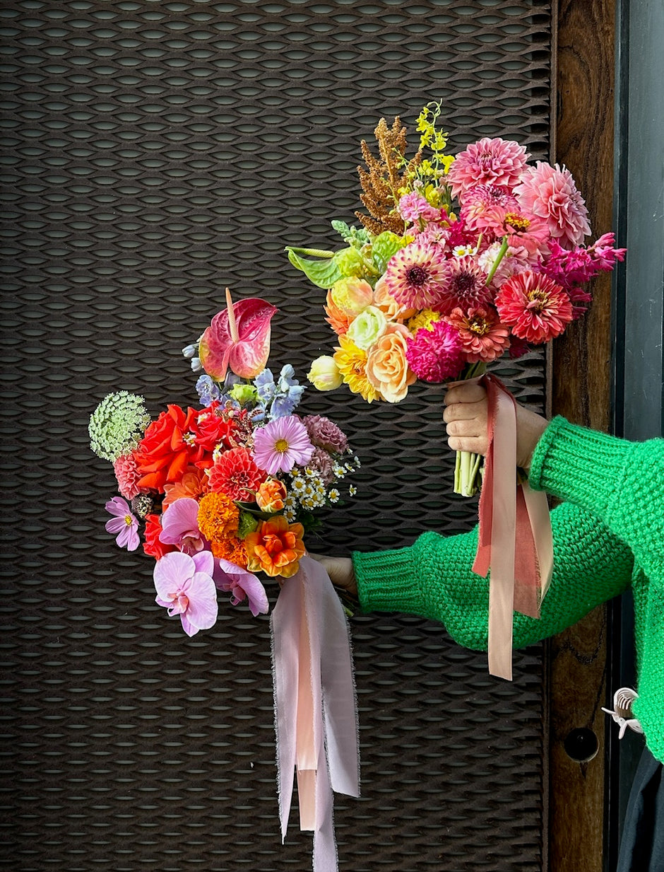 Person holding a colourful bridal bouquet of flowers against a dark textured background