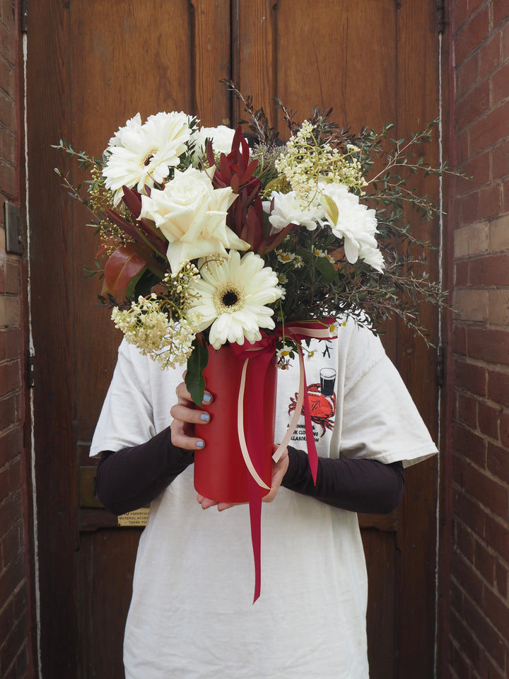 Person holding a bouquet of flowers in front of a wooden door.