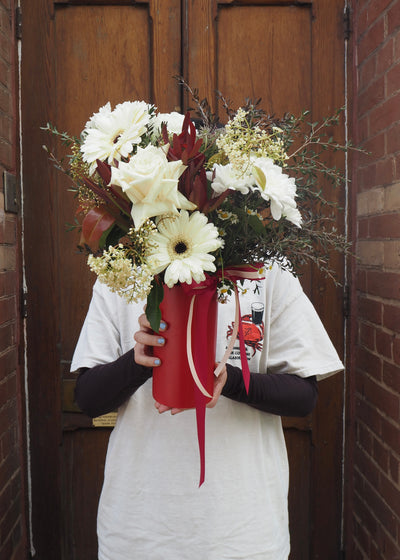 Person holding a bouquet of flowers in front of a wooden door.