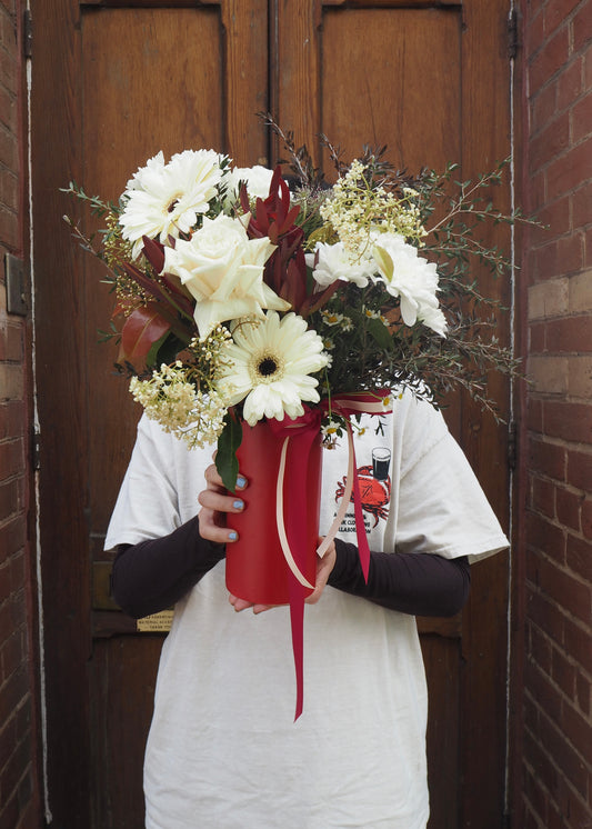 Person holding a bouquet of flowers in front of a wooden door.