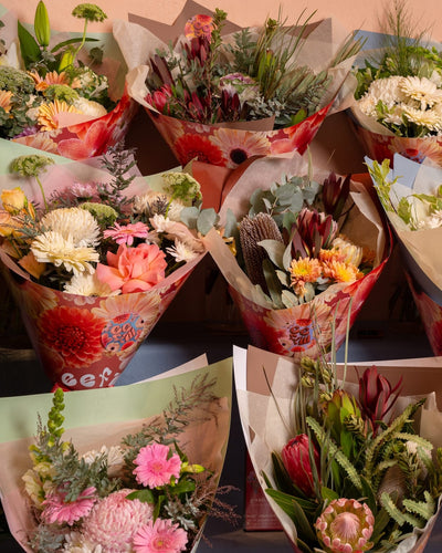 Various flower bouquets in different wrapping styles on a table.