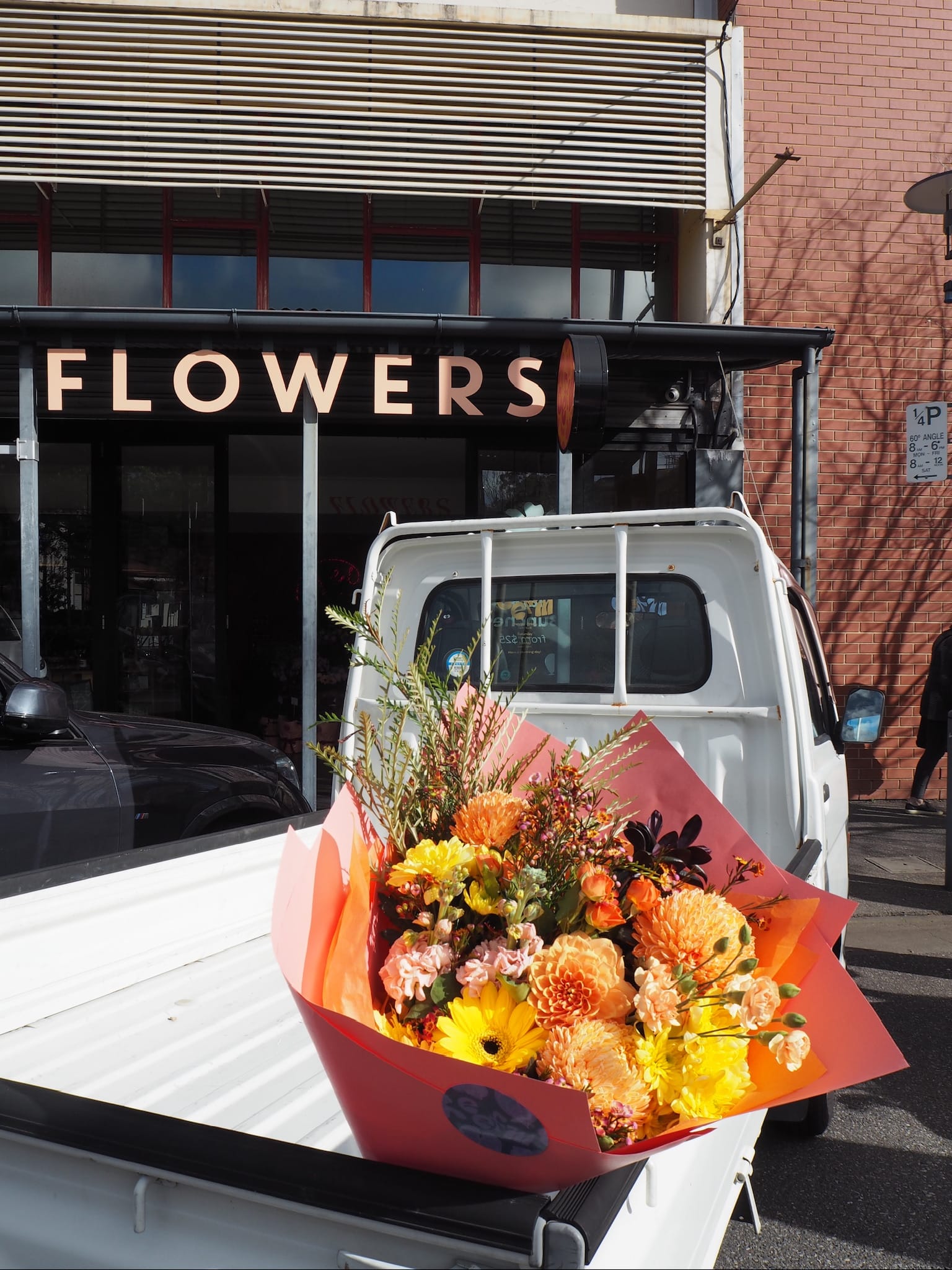 Floral arrangement in the back of a van with a 'Flowers' sign in the background.