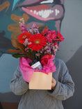 Load image into Gallery viewer, Person holding a bouquet of flowers with a card against a colorful wall.
