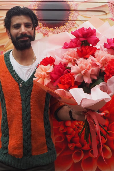 Man holding flowers in front of a decorated van with floral designs.