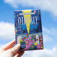 Load image into Gallery viewer, A hand holding a bar of OTHERLY Vegan Chocolate with a colorful and illustrated packaging depicting various characters and a birthday cake.
