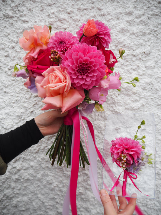 Bridal bouquet of pink flowers (roses, dahlias, canterbury bells) with ribbons against a textured white background