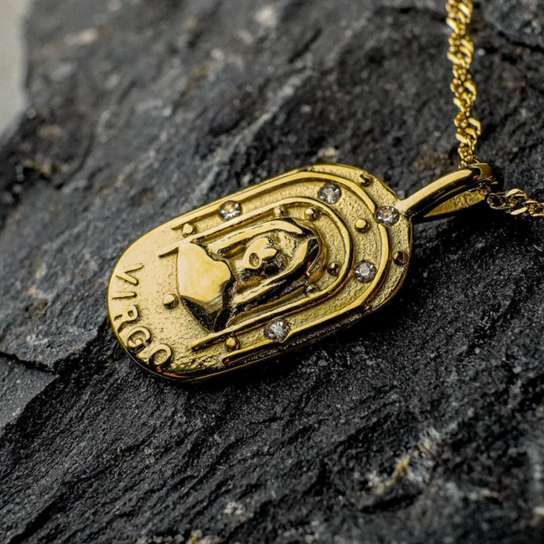 Gold Virgo zodiac pendant on a dark stone surface