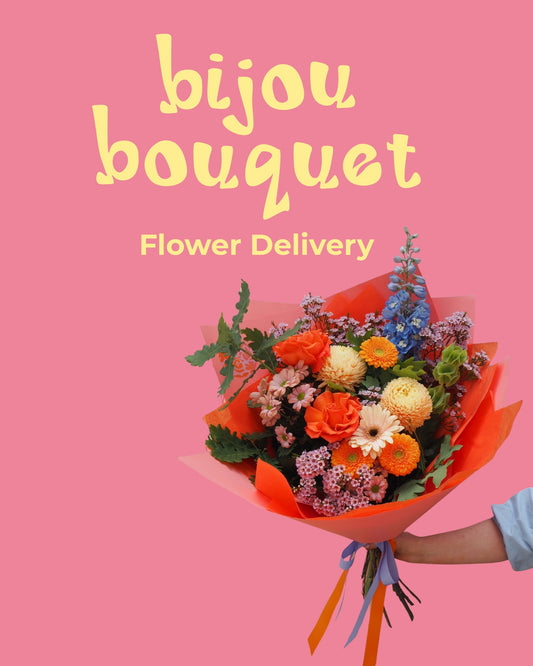Bouquet of flowers held by a person with 'bijou bouquet' text on a pink background