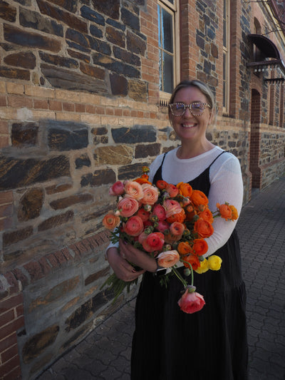 Person holding a bouquet of flowers in front of a brick wall