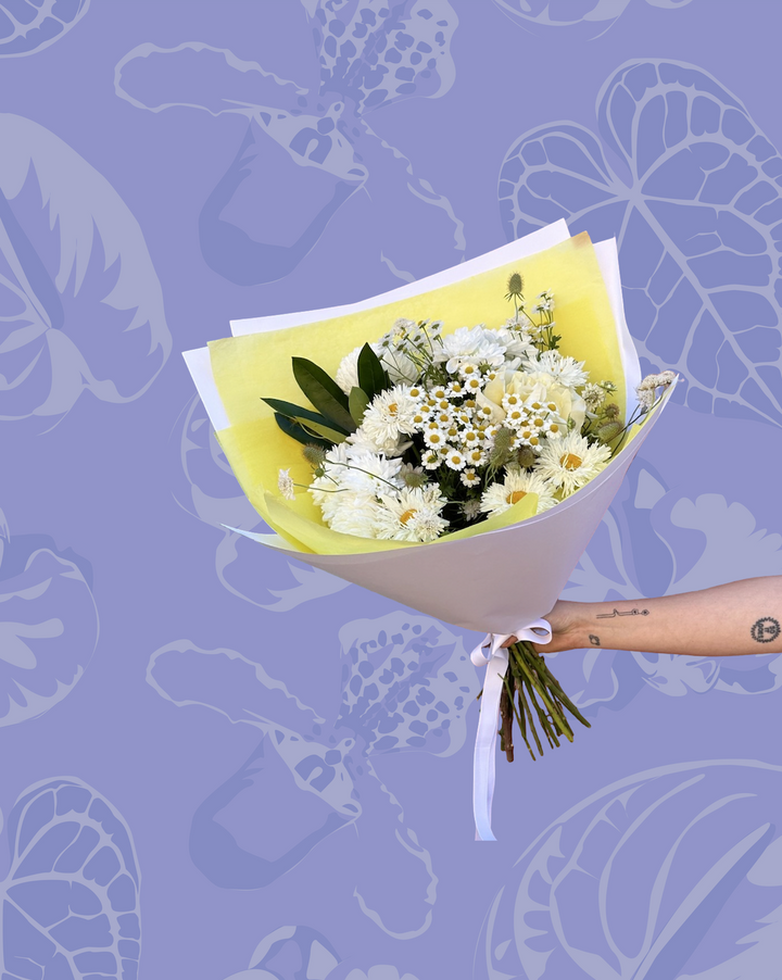 Bouquet of flowers held against a purple background with flower patterns