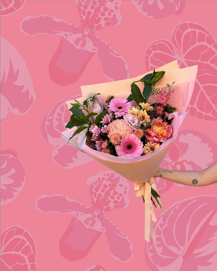 Bouquet of flowers held against a pink background with flower patterns