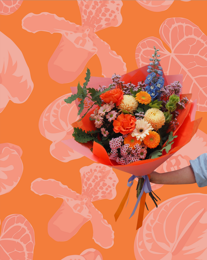 Bouquet of flowers held by a hand on an orange background with floral patterns